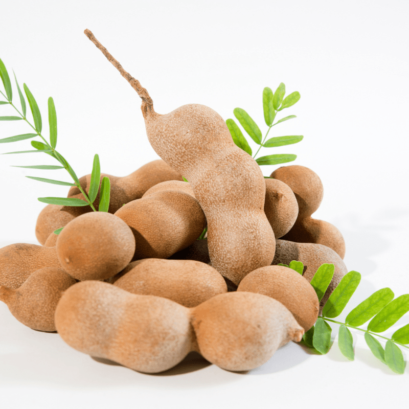 Jamaican sweet tamarind fruit with leaves on white surface